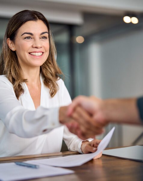 Happy mid aged business woman manager handshaking at office meeting. Smiling female hr hiring recruit at job interview, bank or insurance agent, lawyer making contract deal with client at work.